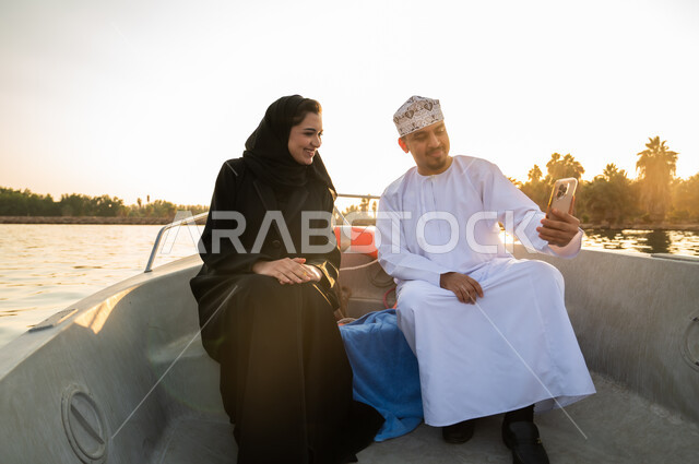 زوجان عمانيان على متن قارب يلتقطان سيلفي وقت الغروب