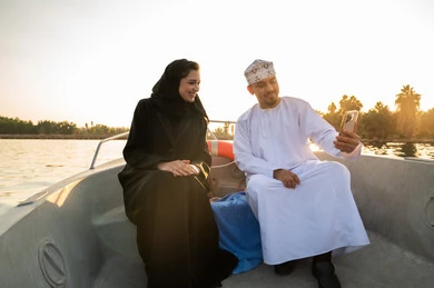 زوجان عمانيان على متن قارب يلتقطان سيلفي وقت الغروب
