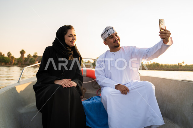 زوجين عمانيين يلتقطان سيلفي على متن قارب وقت الغروب