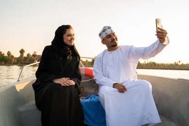 زوجين عمانيين يلتقطان سيلفي على متن قارب وقت الغروب