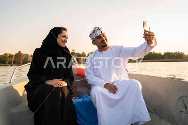 زوجان عمانيان يلتقطان سيلفي على قارب وقت الغروب
