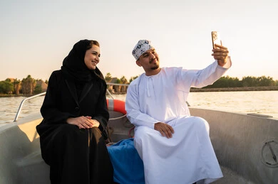 زوجان عمانيان يلتقطان سيلفي على قارب وقت الغروب
