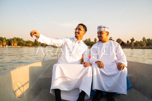 رجال عرب بالزي التقليدي في رحلة بحرية وقت الغروب
