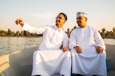رجال عمانيون بالزي التقليدي في قارب عند الغروب