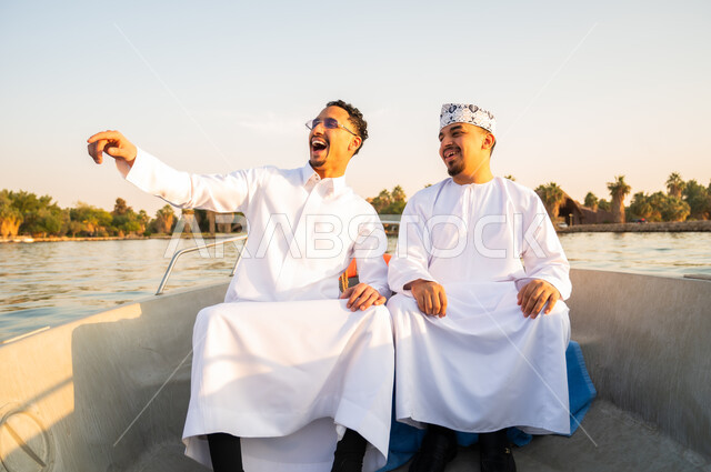 رجال عمانيون بالزي التقليدي في قارب وقت الغروب