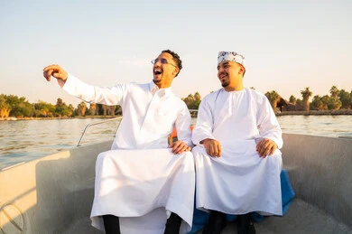 Omani Men in Traditional Dress on Boat at Sunset