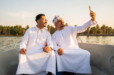 رجلان عُماني وسعودي يلتقطان سيلفي في قارب وقت الغروب