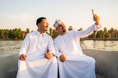 رجال عمانيون يلتقطون سيلفي على قارب وقت الغروب