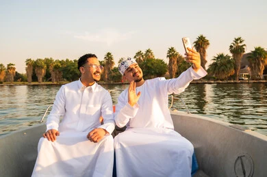 رجال عمانيون باللباس التقليدي يلتقطون سيلفي في قارب