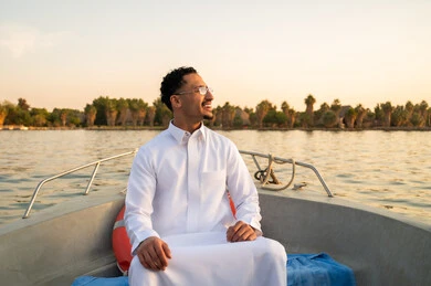رجل سعودي بالثوب التقليدي على قارب وقت الغروب