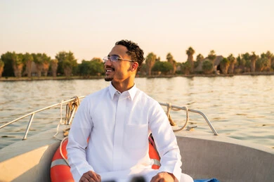 رجل سعودي بالثوب الأبيض على قارب وقت الغروب