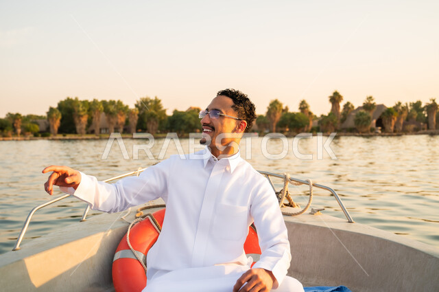 رجل سعودي بالثوب الأبيض في قارب وقت الغروب