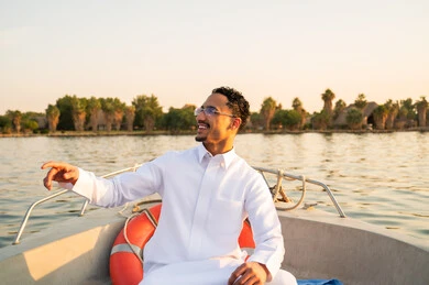 رجل سعودي بالثوب الأبيض في قارب وقت الغروب