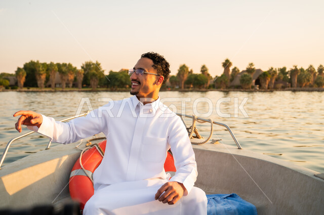 رجل سعودي بالثوب التقليدي في قارب وقت الغروب