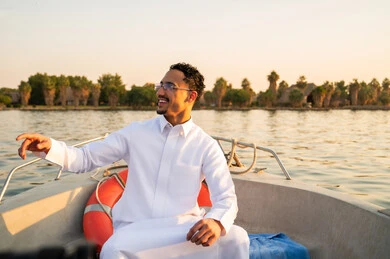 رجل سعودي بالثوب التقليدي في قارب وقت الغروب