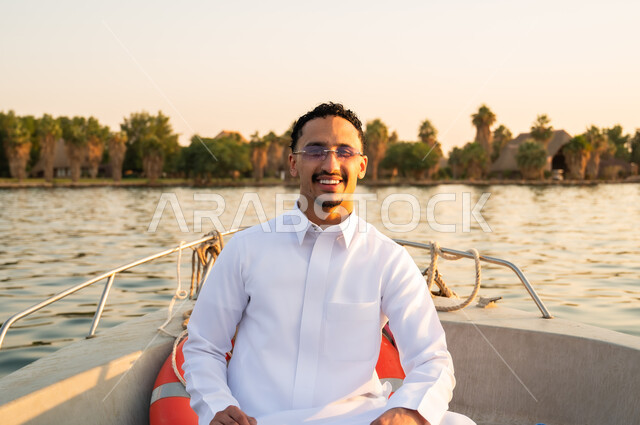 رجل سعودي بالثوب الأبيض على متن قارب وقت الغروب