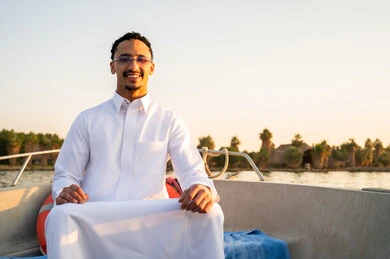 رجل سعودي بالثوب الأبيض على قارب وقت الغروب