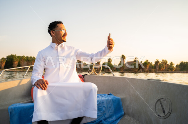 رجل سعودي بالثوب الأبيض يلتقط سيلفي في القارب