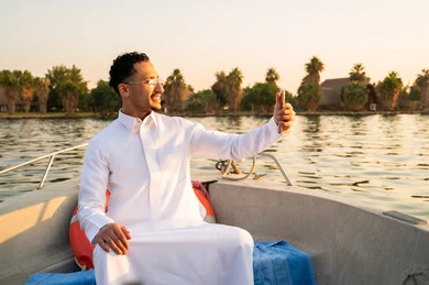 رجل سعودي يلتقط سيلفي على قارب وقت الغروب