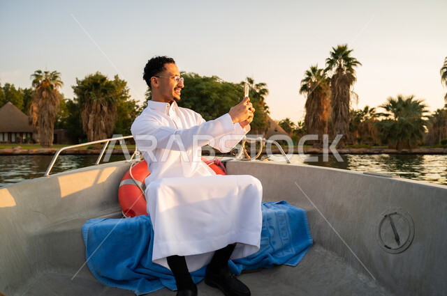 Saudi Man in Thobe Taking Selfie on Boat at Sunset