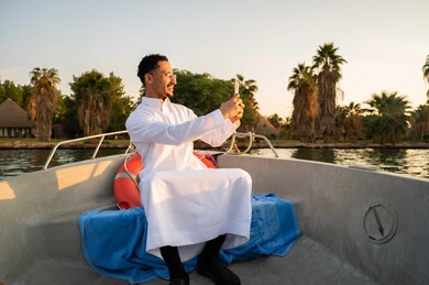 Saudi Man in Thobe Taking Selfie on Boat at Sunset
