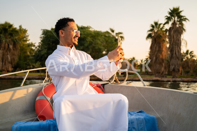 شاب سعودي بالثوب الأبيض يلتقط سيلفي على قارب