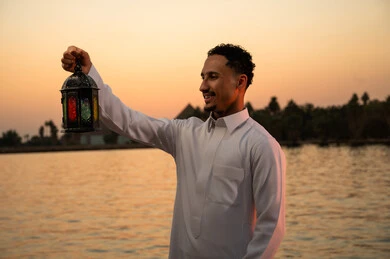 رجل سعودي يحمل فانوساً عربياً وقت الغروب