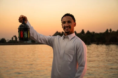 Saudi Man Holding Ramadan Lantern at Sunset Lake
