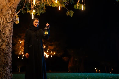 امرأة سعودية تحمل فانوساً تقليدياً في الليل