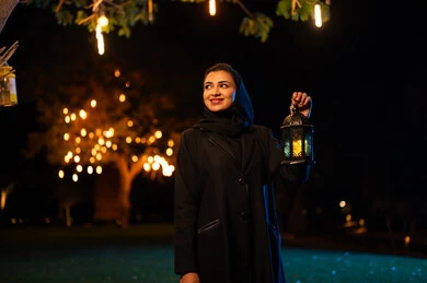 امرأة سعودية تحمل فانوساً تقليدياً في الليل