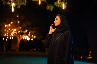امرأة سعودية بالعباءة السوداء تستخدم الهاتف في الليل