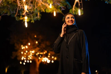 امرأة سعودية بالعباءة تستخدم الهاتف الذكي ليلاً