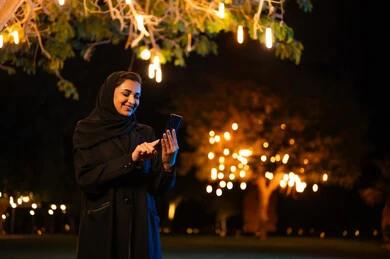 امرأة سعودية تستخدم الهاتف الذكي ليلاً