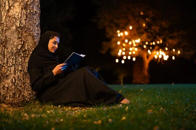 Saudi Woman Reading Book in Night Park Setting