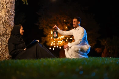 زوجان سعوديان مع فانوس رمضان في الحديقة ليلاً