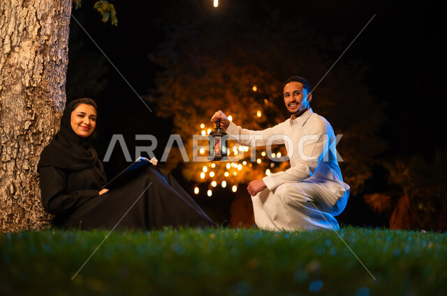زوجين سعوديين مع فانوس تقليدي في حديقة ليلية