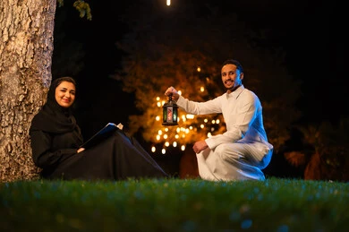 زوجين سعوديين مع فانوس تقليدي في حديقة ليلية زوجين سعوديين مع فانوس تقليدي في حديقة ليلية