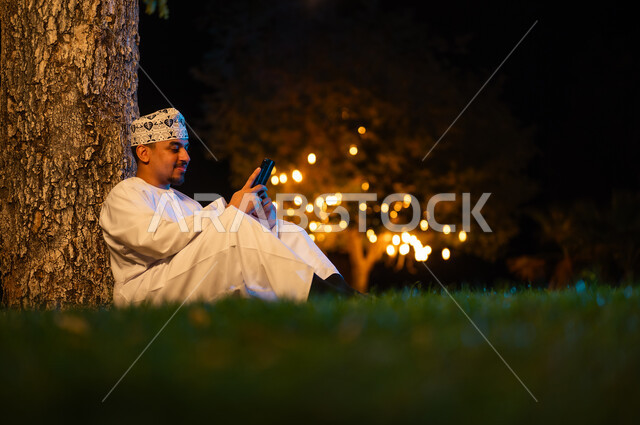 Omani Man with Smartphone in Night Park