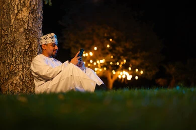 Omani Man with Smartphone in Night Park