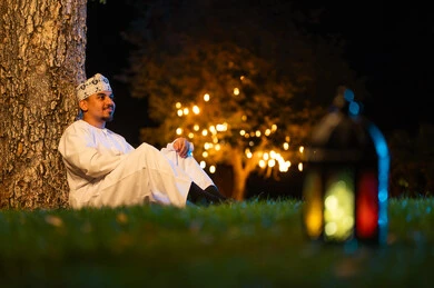 رجل عماني بالزي التقليدي مع فانوس ليلاً