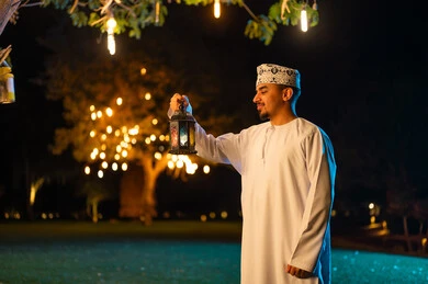 رجل عُماني يحمل فانوساً تقليدياً في الليل