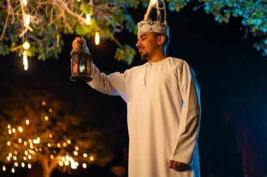 رجل عماني يحمل فانوساً في الخارج ليلاً