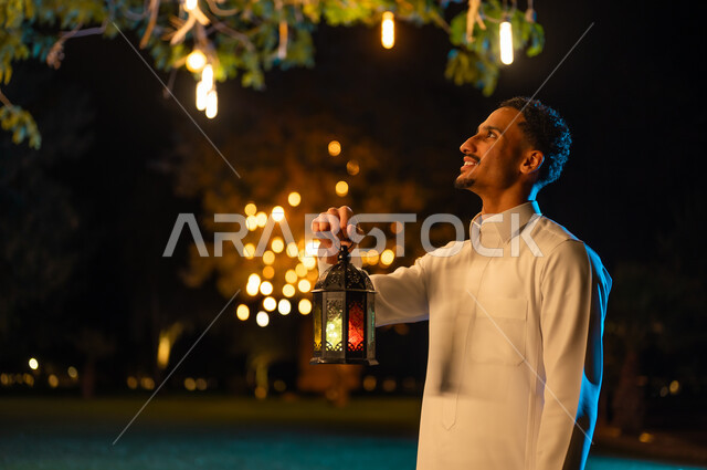 رجل سعودي يمسك فانوس رمضان المضيء في الليل