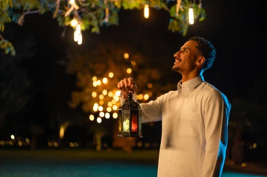 رجل سعودي يمسك فانوس رمضان المضيء في الليل
