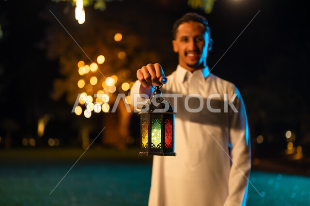 رجل سعودي يمسك فانوس رمضان مضاء في الليل