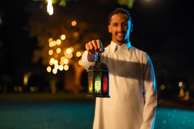 رجل سعودي يمسك فانوس رمضان مضاء في الليل