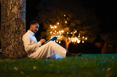 رجل سعودي يقرأ كتاباً في حديقة ليلاً