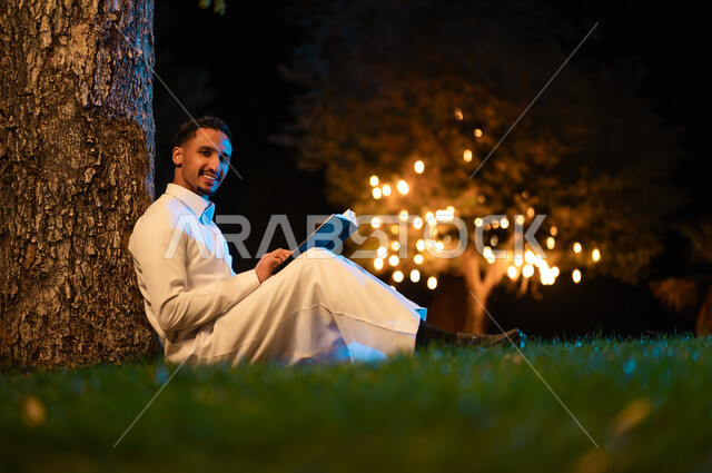 Saudi Man Reading Book Under Tree in Night Garden