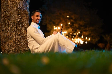 رجل سعودي يستخدم الجهاز اللوحي في حديقة ليلاً