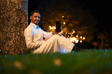 رجل سعودي مع هاتف ذكي في حديقة ليلية